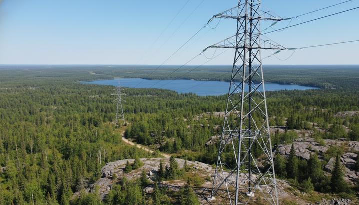 Новая опора высоковольтной линии электропередачи на фоне скалистого ландшафта и бореального леса в Саскачеване, Канада.