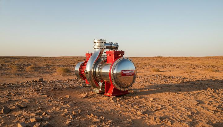 Weir и Olayan создают СП для поддержки горной промышленности Саудовской Аравии Крупный промышленный шламовый насос красного цвета на фоне скалистого пустынного ландшафта Саудовской Аравии на закате.